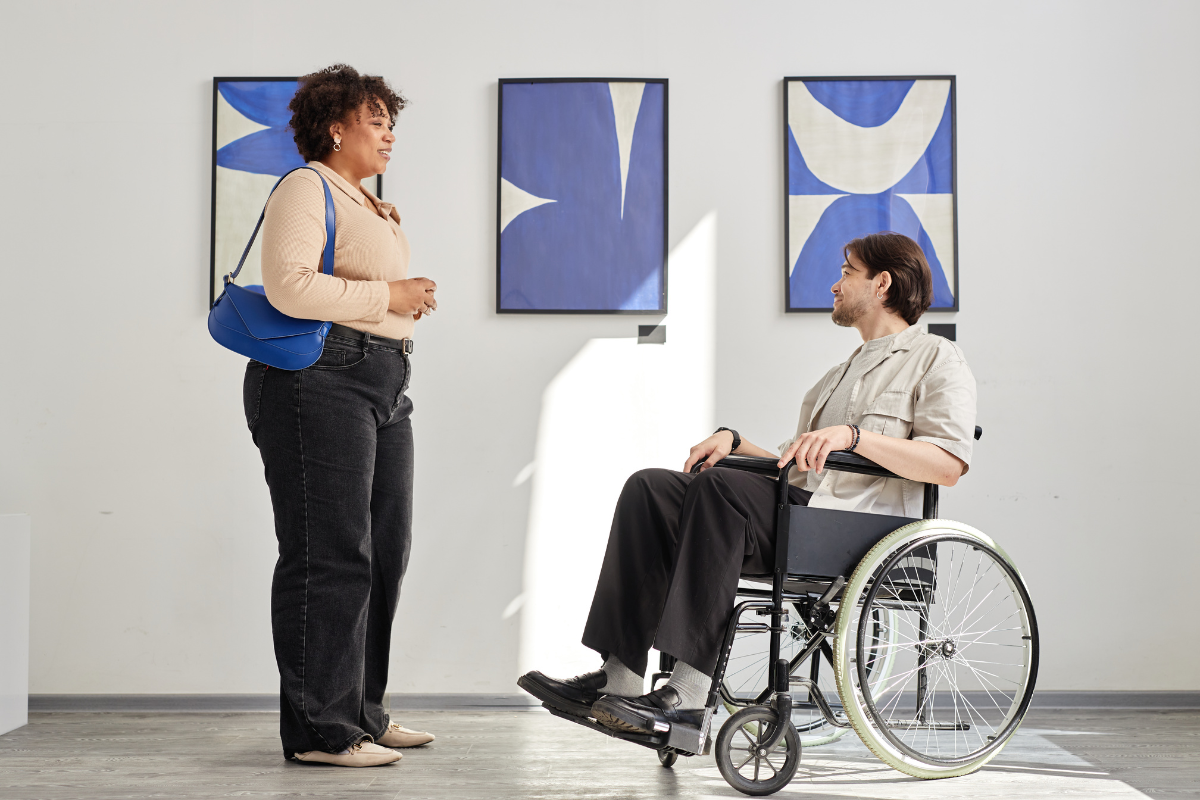 woman talking to man in wheelchair in gallery